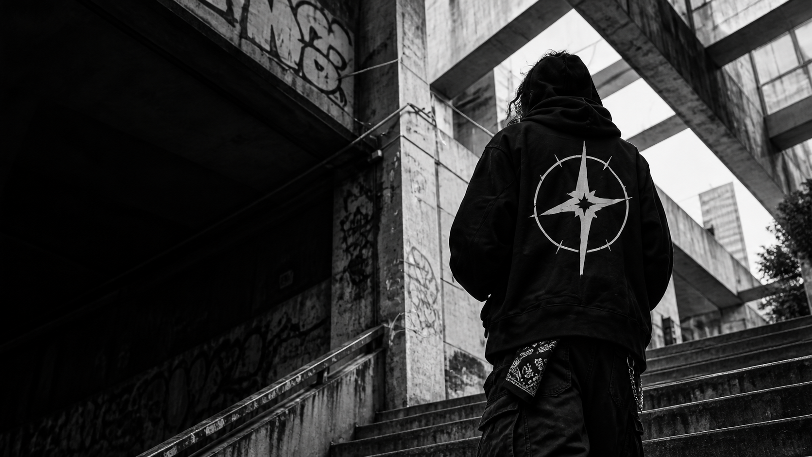 Persona con hoodie gráfico en una escalera de concreto.